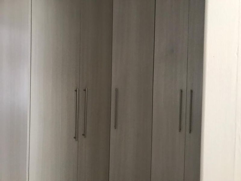 A close-up view of modern, neutral-toned built-in bedroom cupboards with sleek metal handles.