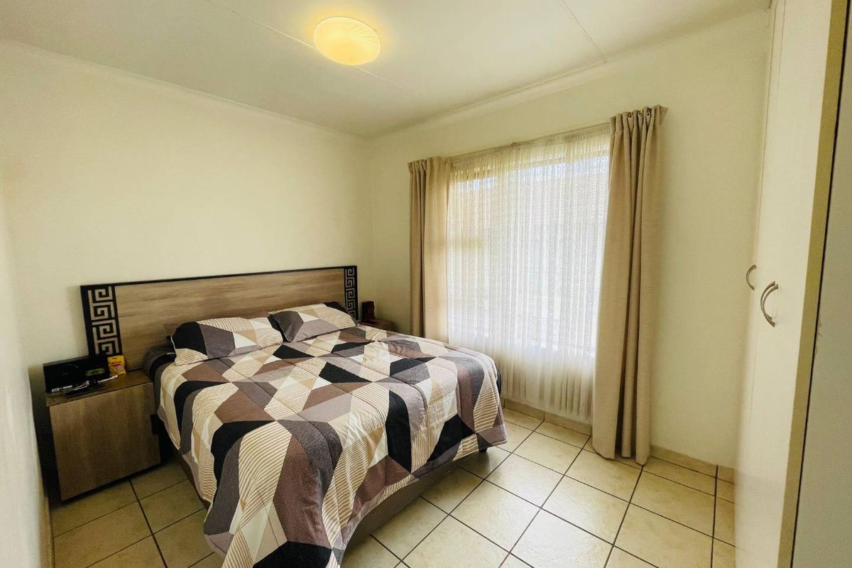 A bedroom featuring tiled flooring and built-in wardrobe storage, offering a functional and neutral living space.