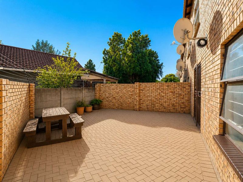 A private outdoor patio area featuring paved flooring and enclosed by brick boundary walls, providing a functional space for outdoor relaxation.