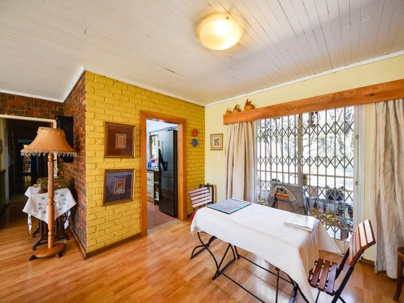 Dining area featuring exposed brick walls, laminate flooring, and a sliding glass door with a security gate leading to the exterior.