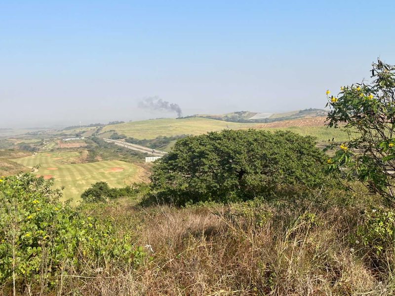 A scenic elevated view overlooking a golf course and surrounding rolling hills, showcasing the natural landscape and terrain of the vacant residential property.