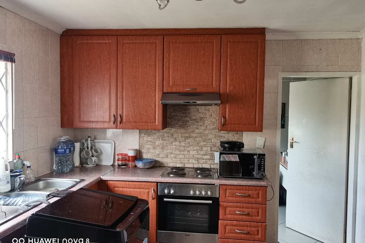 A functional kitchen featuring wood-finish cabinetry, a built-in oven with extractor fan, and a tiled backsplash, offering a practical layout for daily meal preparation.