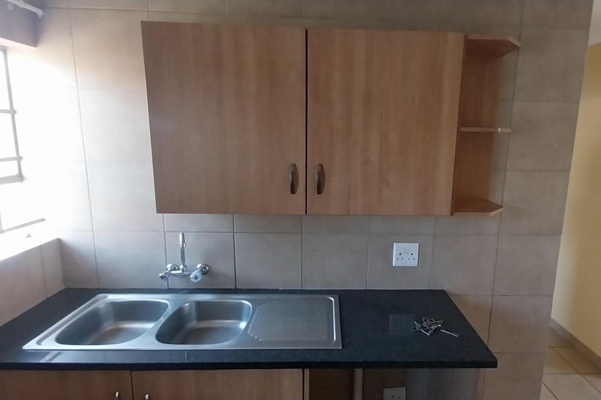 A functional kitchen area featuring laminate cabinetry, a double bowl stainless steel sink, granite countertops, and tiled wall finishes.