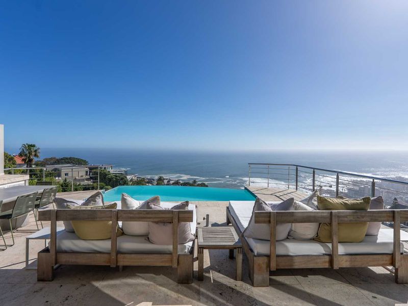 An expansive outdoor terrace featuring an infinity-edge swimming pool with panoramic ocean views and modern stone paving.