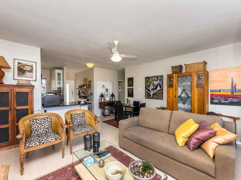 Open-plan living and dining area featuring tiled flooring, a ceiling fan, and a functional kitchen with granite countertops.