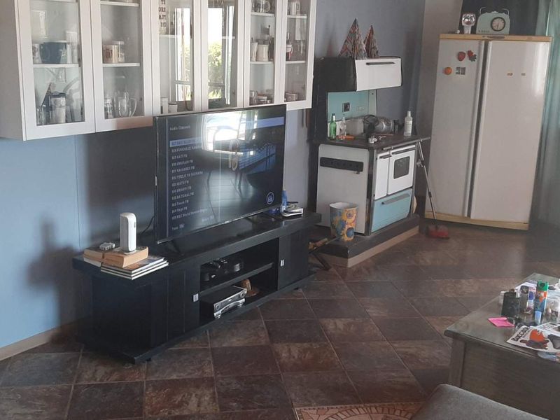 A living area featuring tiled flooring and built-in wall cabinetry, providing a functional space with a vintage-style stove integrated into the room layout.