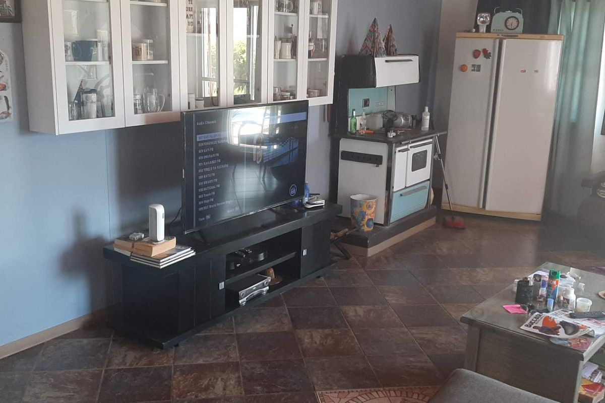 A living area featuring tiled flooring and built-in wall cabinetry, providing a functional space with a vintage-style stove integrated into the room layout.