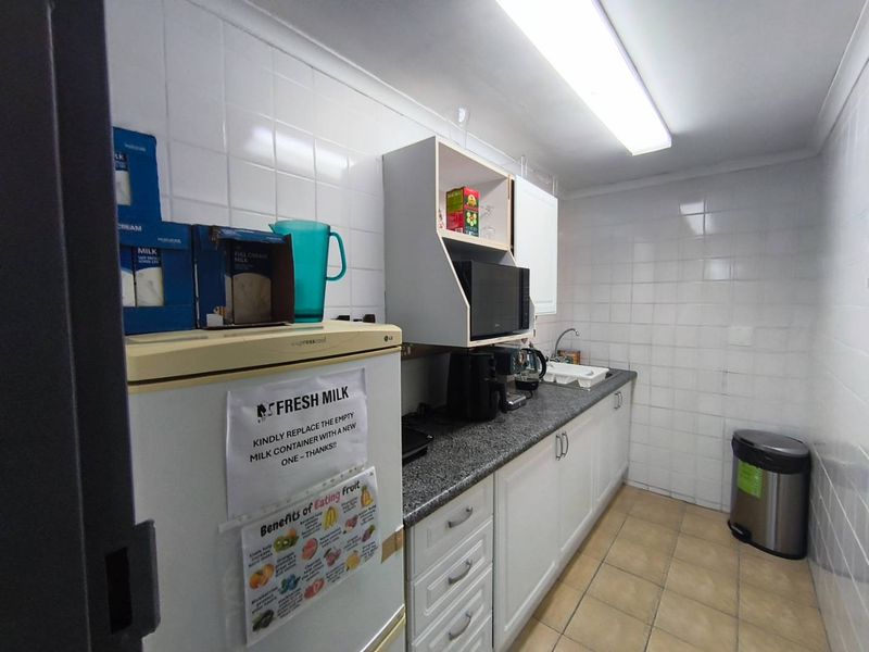 A functional scullery area featuring tiled walls, granite countertops, and built-in cabinetry with a stainless steel sink.