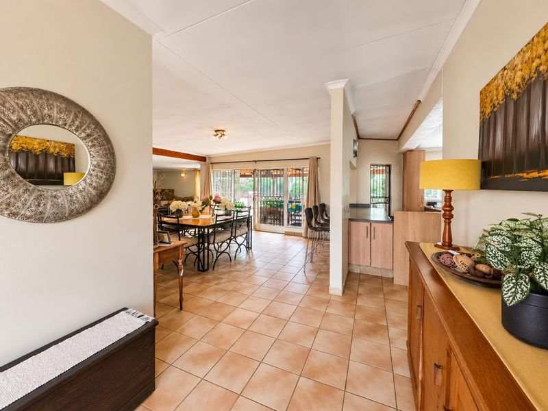 Spacious open-plan living and dining area featuring ceramic floor tiles, neutral walls, and direct access to the outdoor patio through sliding glass doors.