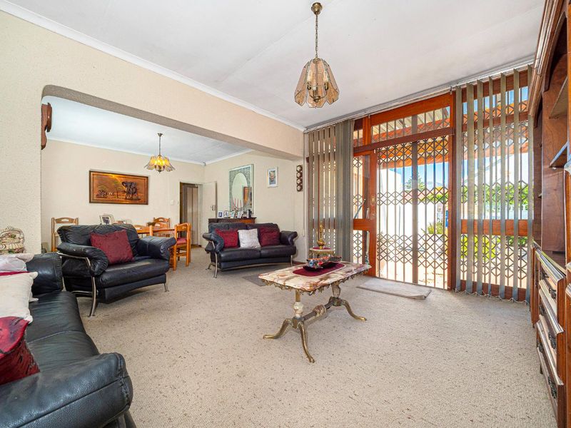 Open plan living and dining area featuring neutral walls, carpeted flooring, and direct access to the exterior through a secure entrance.