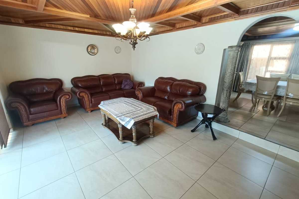 Spacious living area featuring a distinctive timber vaulted ceiling, ceramic tiled flooring, and an elegant archway leading to the adjacent dining space.