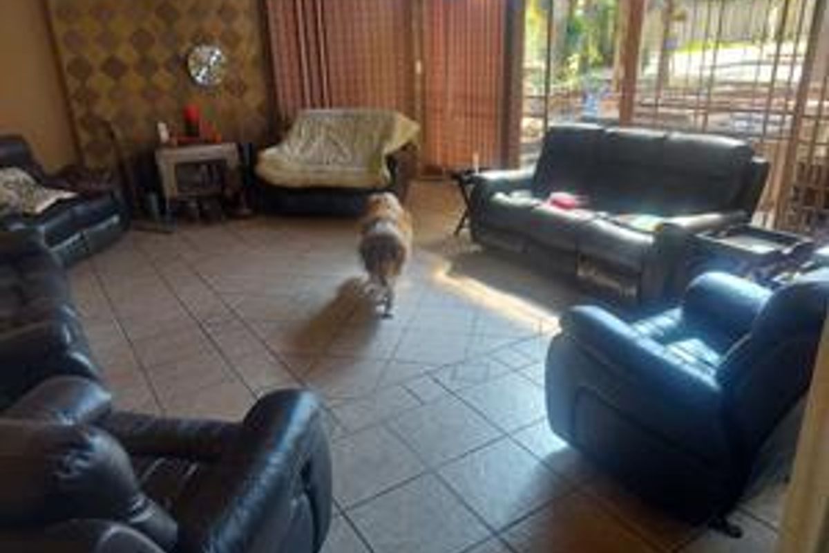 Spacious living area featuring tiled flooring, large windows with vertical blinds, and direct access to the outdoor patio area.