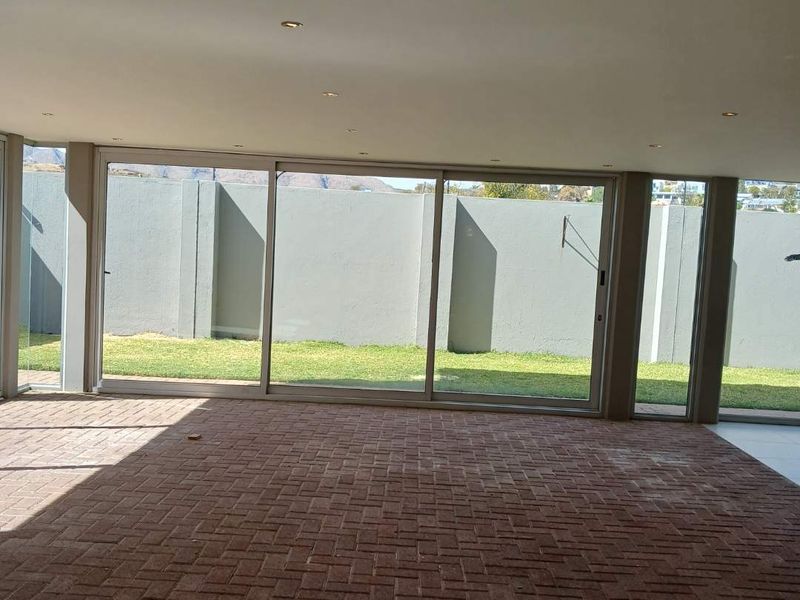 Spacious covered patio featuring brick paving, recessed lighting, and large sliding glass doors opening to a private garden area.