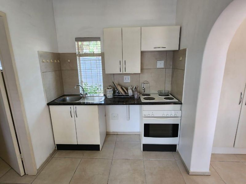 Compact kitchen featuring built-in cabinetry, a stainless steel sink, and an integrated electric stove and oven with tiled backsplash.