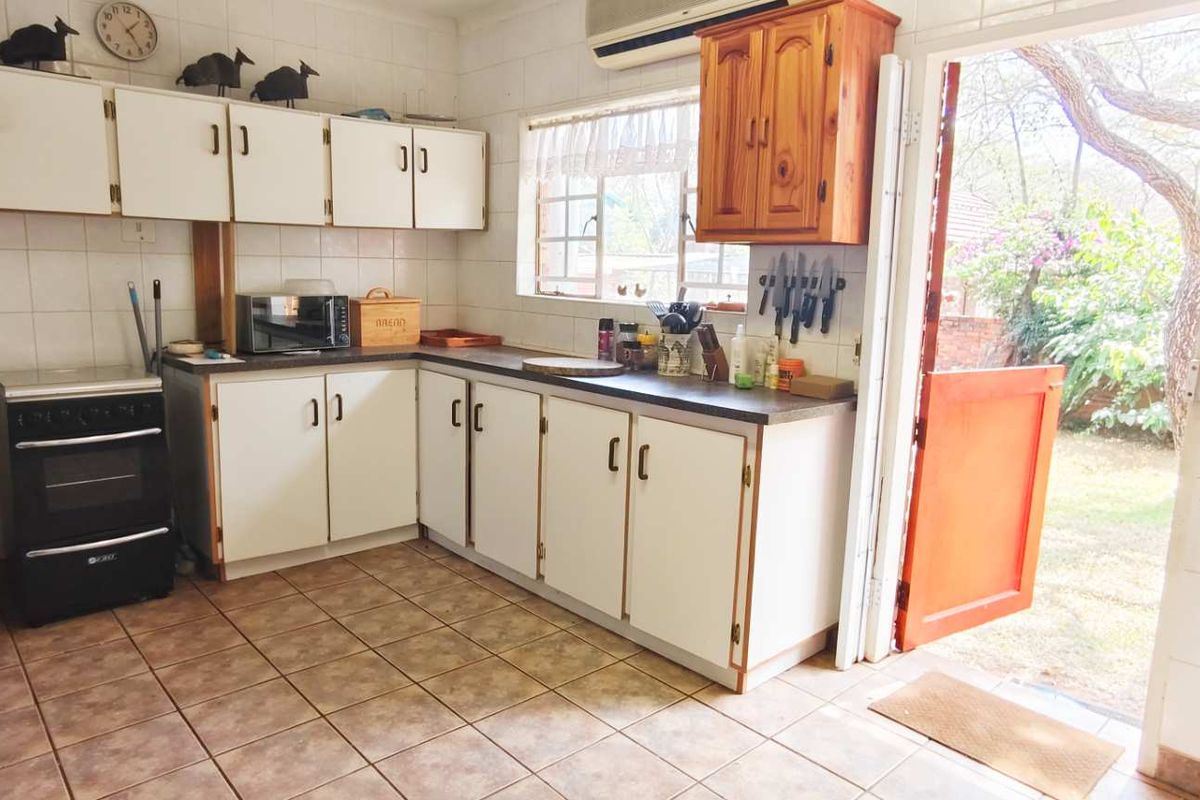 A functional kitchen featuring white cabinetry, tiled flooring, and direct access to the rear garden area.