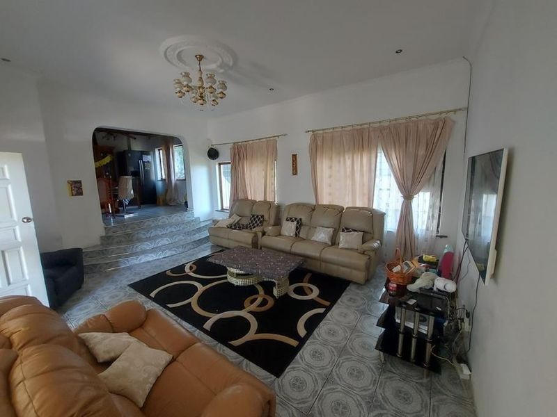 Spacious living room featuring tiled flooring, a decorative ceiling rose, and an arched opening leading to an adjacent area.