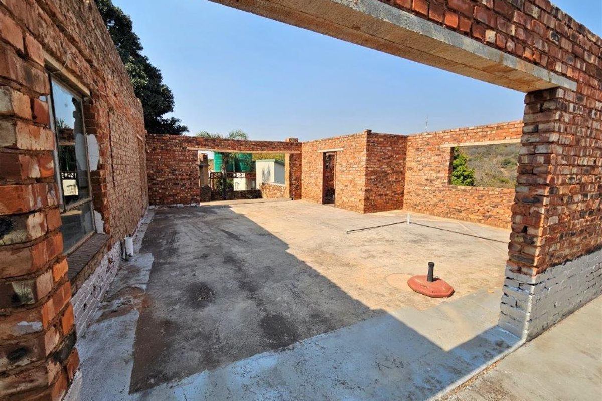 An unfinished construction site showing exposed brick walls and concrete flooring, offering a blank canvas for development on this small holding property.