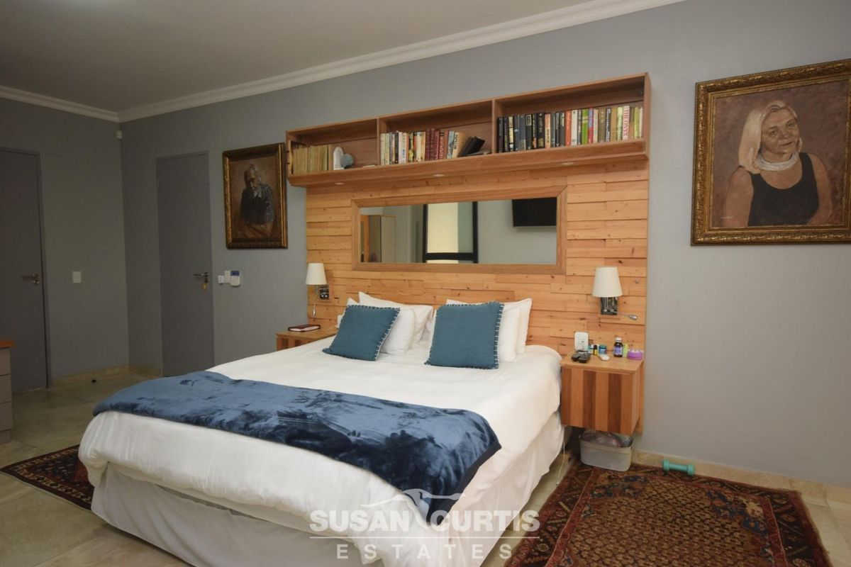 A bedroom featuring a built-in timber headboard with integrated shelving, mirror, and bedside lighting.