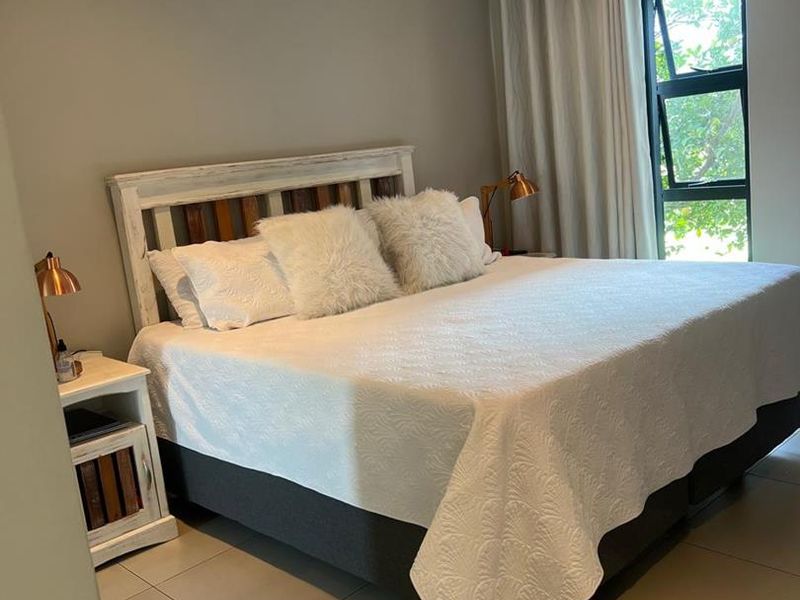 A well-maintained bedroom featuring tiled flooring, a split-system air conditioner, and large windows allowing for natural light.