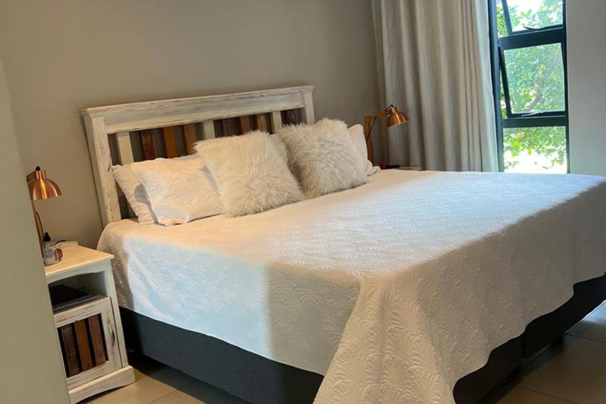 A well-maintained bedroom featuring tiled flooring, a split-system air conditioner, and large windows allowing for natural light.