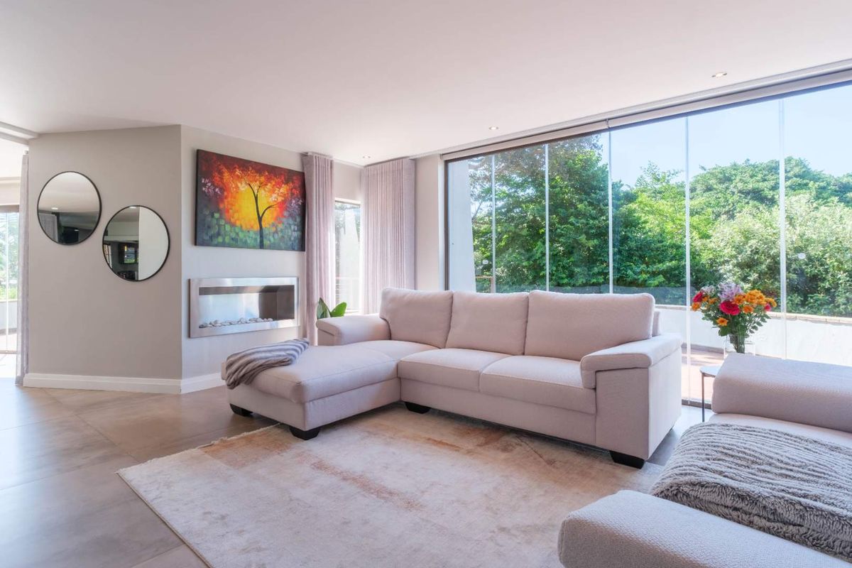 Bright and modern living room featuring a built-in fireplace, large floor-to-ceiling glass sliding doors, and neutral tiled flooring.