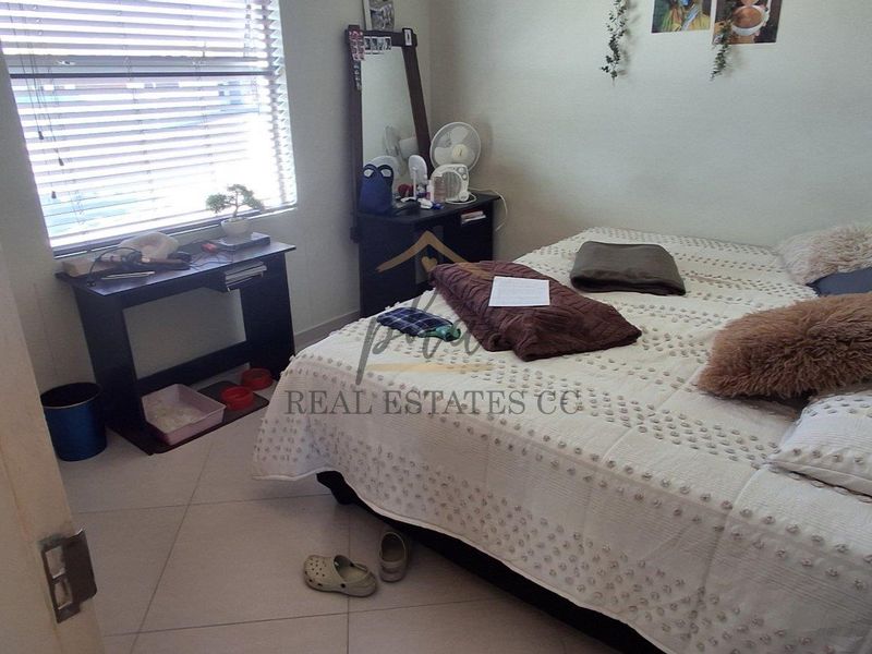 A functional bedroom featuring tiled flooring and venetian blinds, providing a neutral base for personalization.