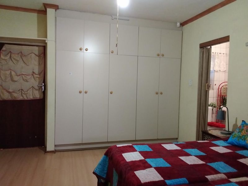 A bedroom featuring extensive built-in cupboards, laminate flooring, and direct access to an adjoining bathroom.