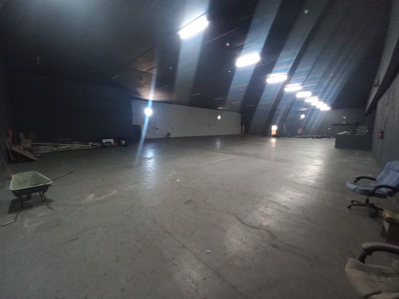 A large, open-plan industrial utility space featuring concrete flooring and overhead fluorescent lighting, suitable for storage or workshop use.
