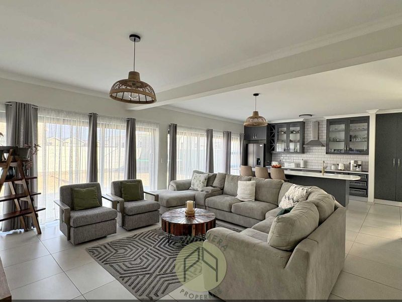Spacious open-plan living area featuring a modern kitchen with island, subway tile backsplash, and large sliding doors leading to the exterior.