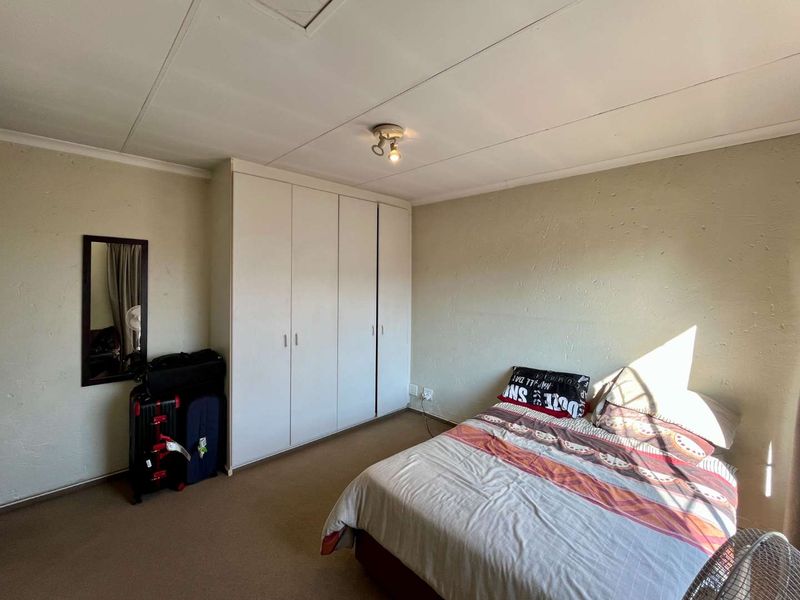 A bedroom featuring built-in floor-to-ceiling wardrobes, carpeted flooring, and a standard ceiling light fixture.