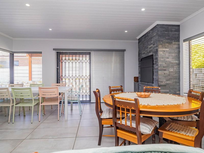 Spacious open-plan living and dining area featuring tiled floors, a striking stone-clad fireplace, and large sliding doors leading to the outdoor space.