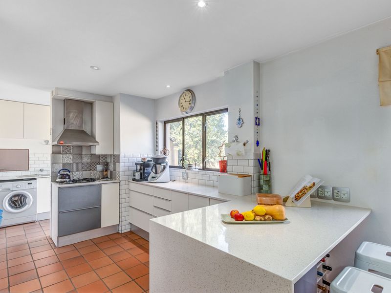 Functional kitchen featuring quartz countertops, subway tile backsplash, gas hob with extractor, and integrated laundry facilities.