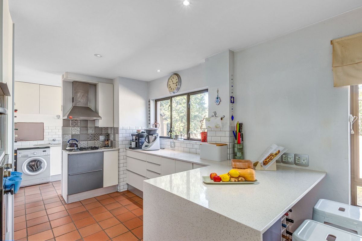 Functional kitchen featuring quartz countertops, subway tile backsplash, gas hob with extractor, and integrated laundry facilities.