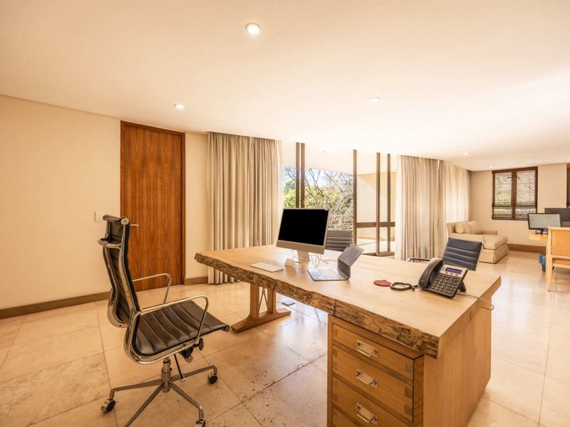 Spacious executive office featuring stone tile flooring, recessed lighting, and large sliding glass doors providing natural light and access to the exterior.