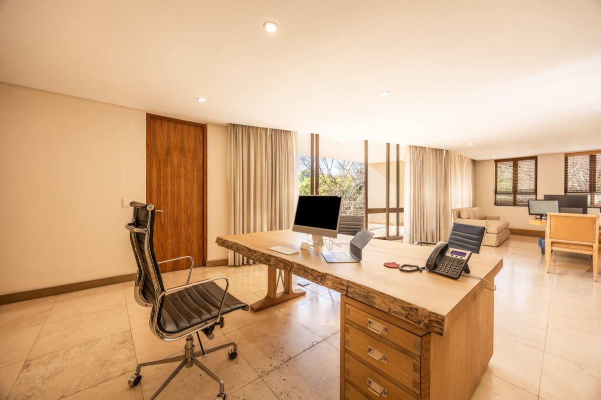 Spacious executive office featuring stone tile flooring, recessed lighting, and large sliding glass doors providing natural light and access to the exterior.