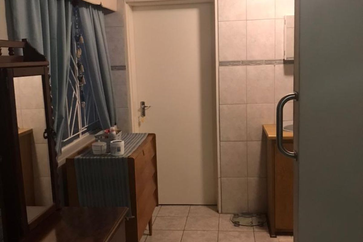 A functional bathroom featuring tiled walls, a timber ceiling, and a built-in vanity unit.