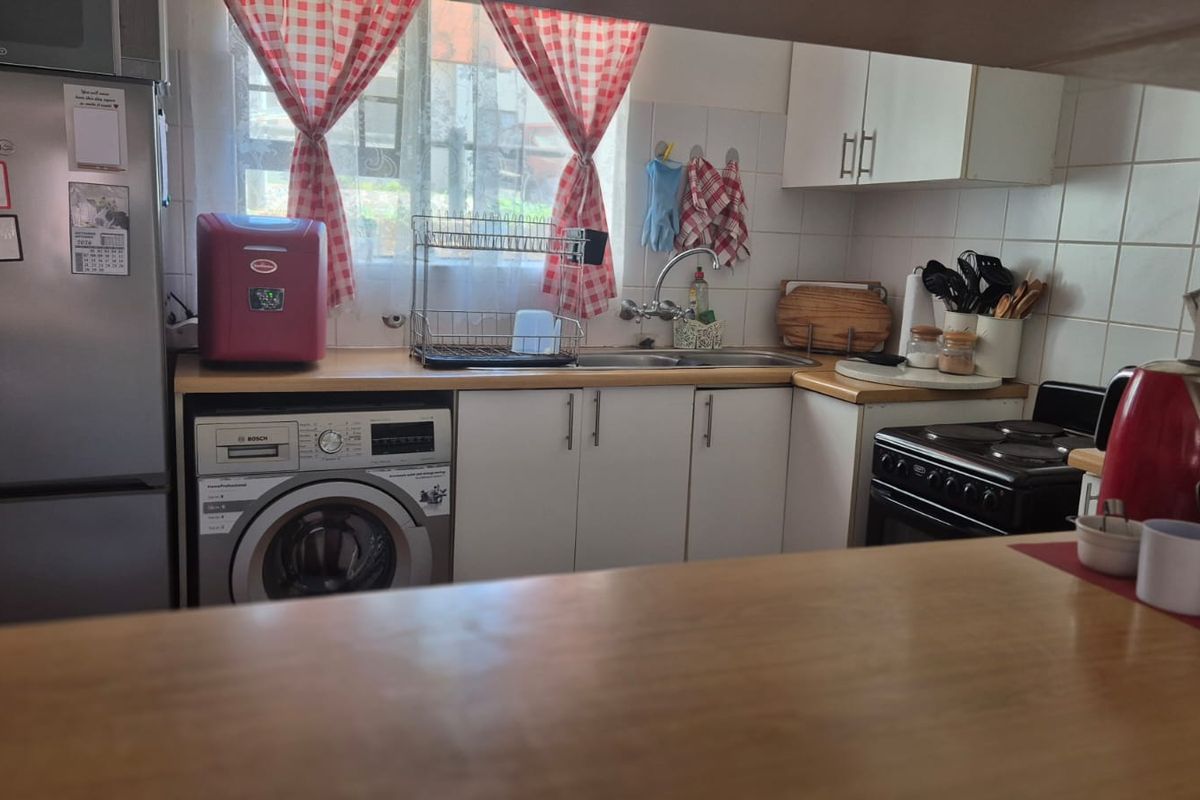 A functional kitchen featuring laminate countertops, white cabinetry, a tiled backsplash, and a built-in washing machine, offering a practical layout for daily use.