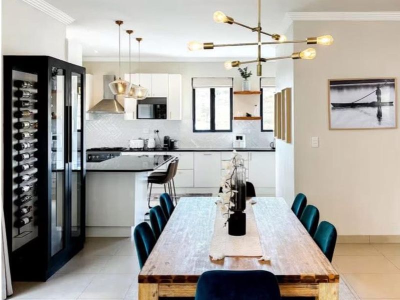 Modern open-plan dining and kitchen area featuring a sleek kitchen island, built-in wine storage, contemporary pendant lighting, and high-quality tiled flooring throughout.