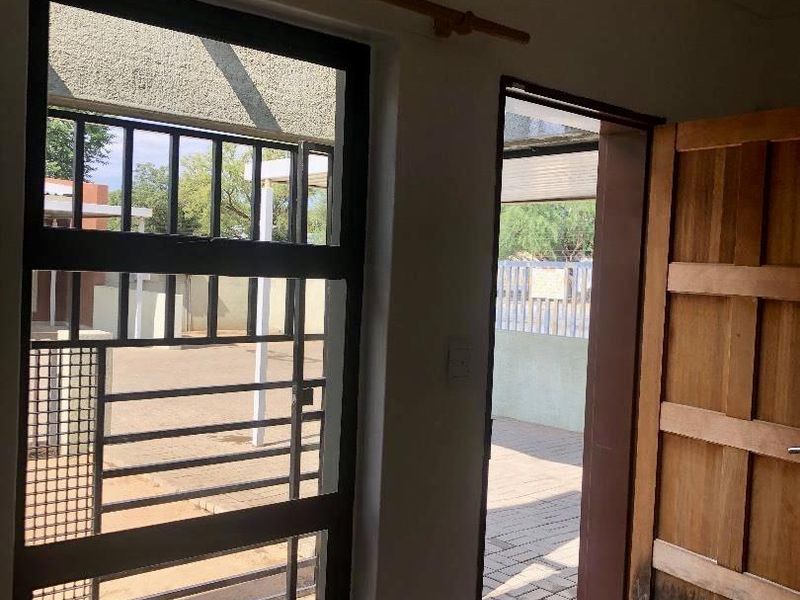 An entry area featuring tiled flooring, a solid timber door, and a security gate providing access to the exterior.
