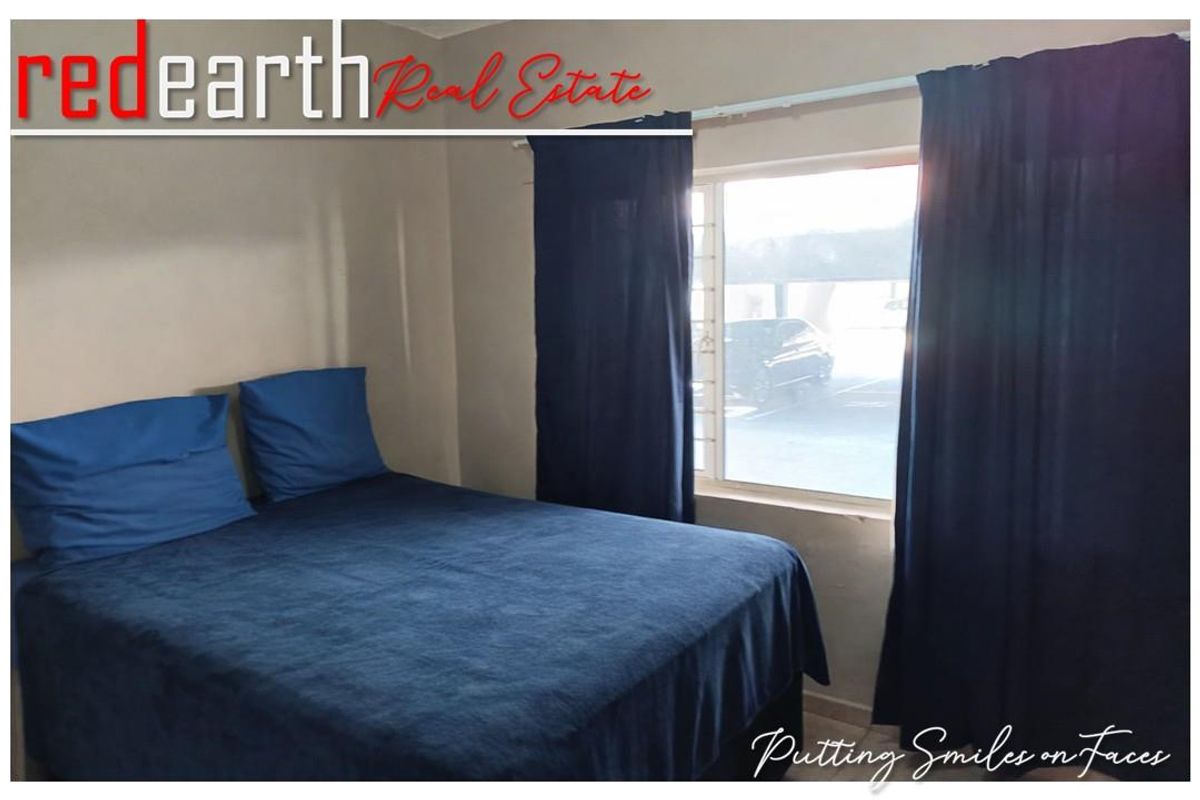 A standard bedroom featuring a window with security bars and neutral wall finishes.