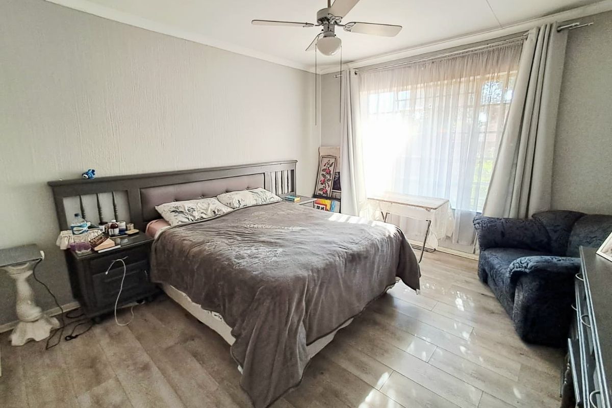 A bedroom featuring laminate flooring, a ceiling fan, and a sliding glass door providing natural light.