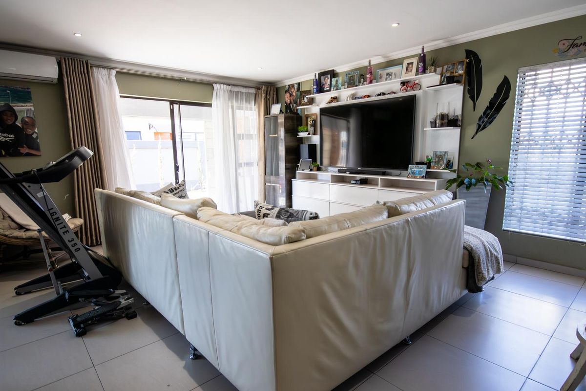 Spacious living room featuring tiled flooring, a built-in media wall unit, recessed lighting, and direct access to the outdoor area via sliding glass doors.