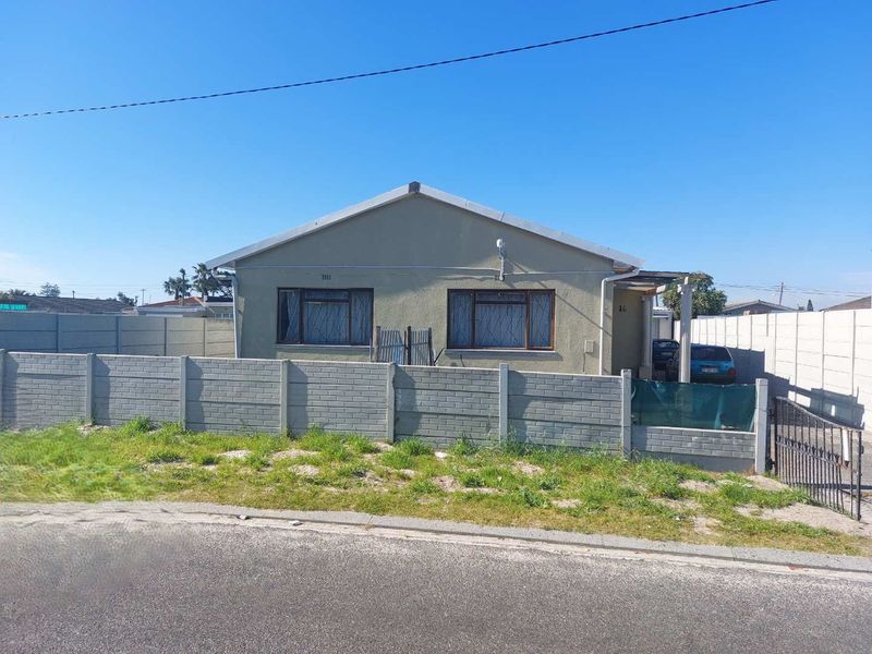 Front elevation of a detached house featuring a precast concrete boundary wall, security gate, and tiled roof with aluminium window frames.