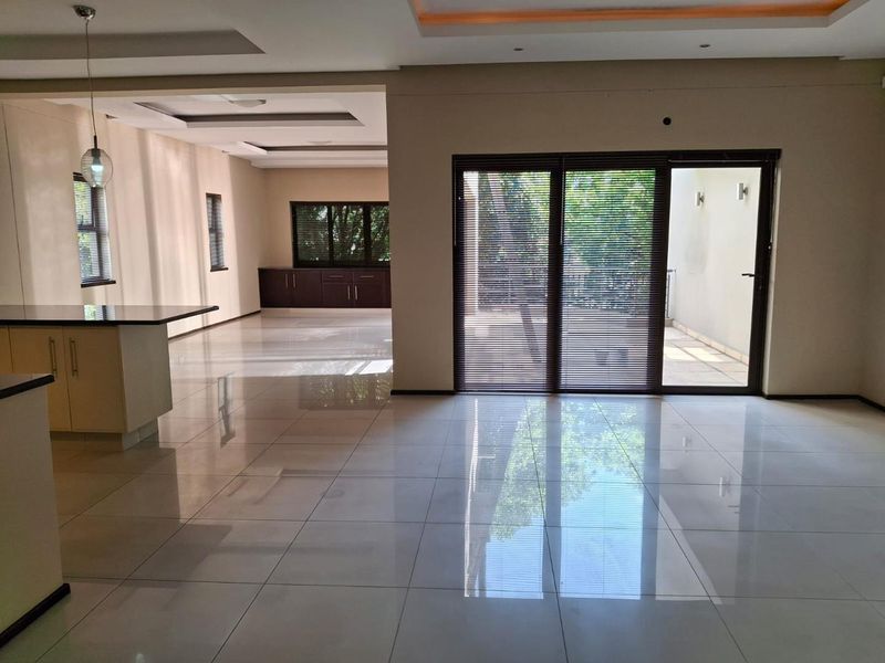 Spacious open-plan living area featuring polished porcelain tiles, recessed ceiling lighting, and large sliding doors leading to an outdoor patio space.