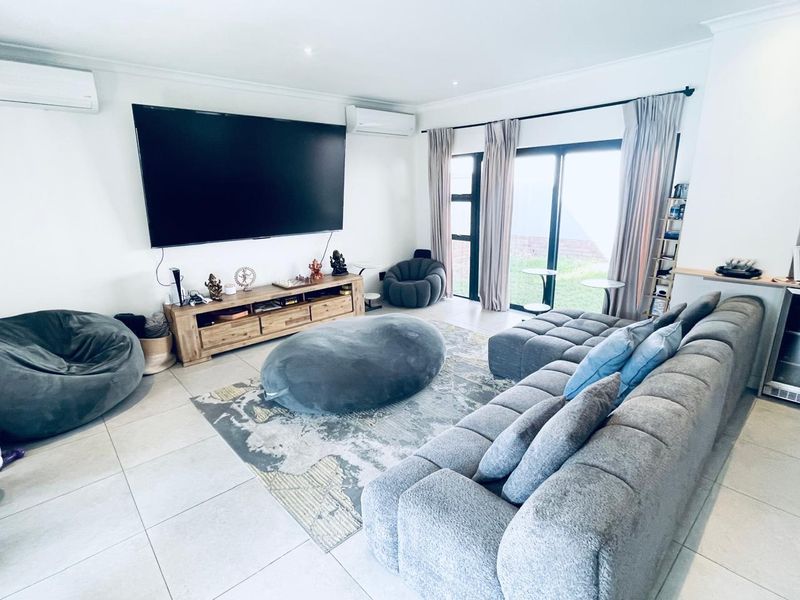 Spacious living room featuring tiled flooring, dual split-system air conditioning units, and large sliding glass doors providing access to the outdoor area.