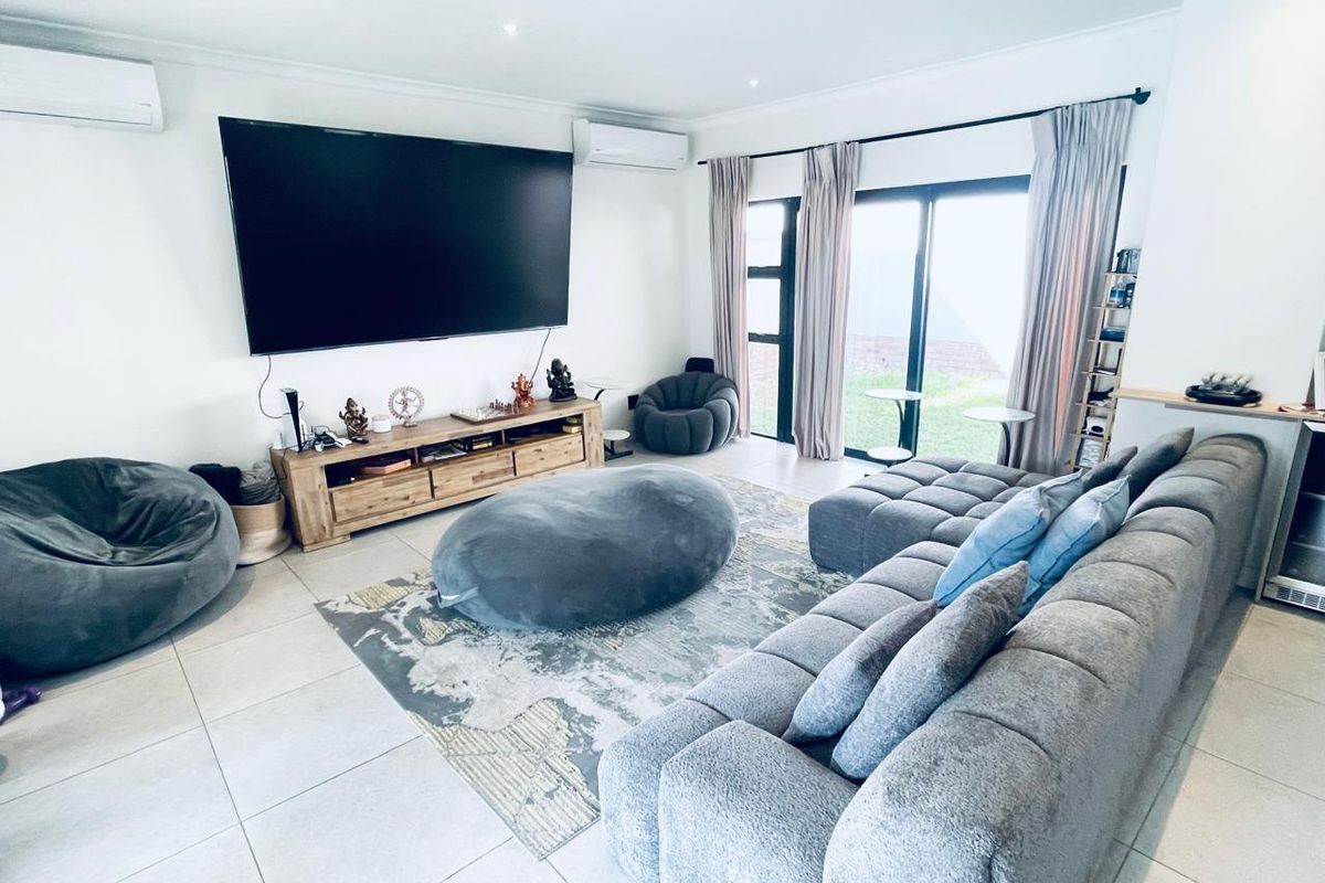 Spacious living room featuring tiled flooring, dual split-system air conditioning units, and large sliding glass doors providing access to the outdoor area.