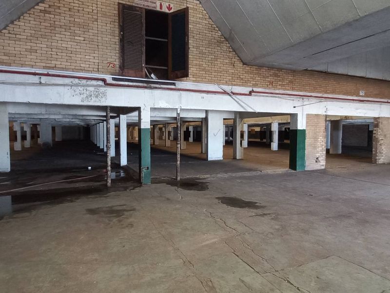 Expansive industrial warehouse space featuring high vaulted ceilings, exposed brickwork, and concrete flooring, suitable for storage or manufacturing operations.