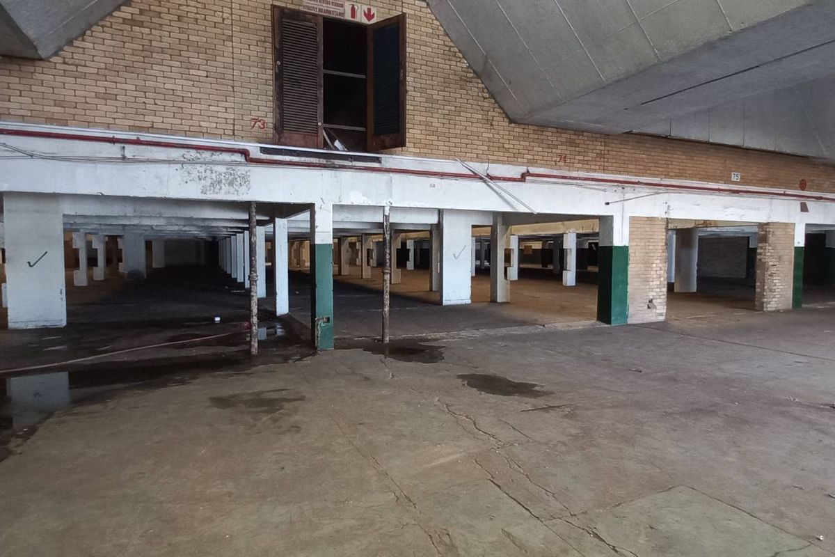 Expansive industrial warehouse space featuring high vaulted ceilings, exposed brickwork, and concrete flooring, suitable for storage or manufacturing operations.