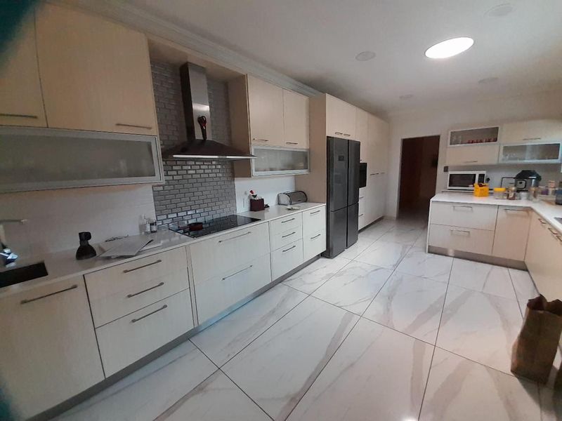 Modern kitchen featuring sleek cabinetry, stone countertops, a subway tile backsplash, and large format floor tiles with integrated appliances.