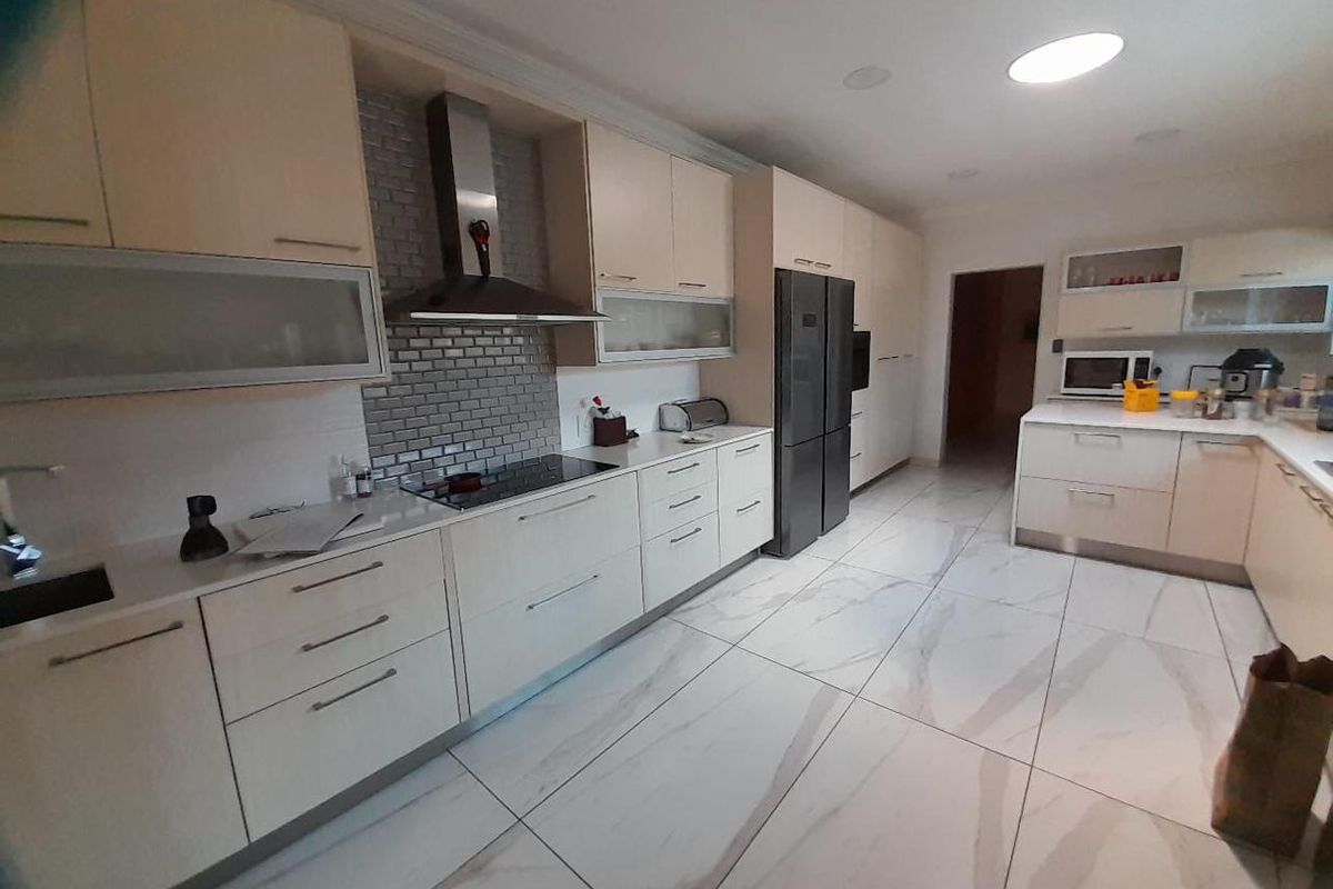 Modern kitchen featuring sleek cabinetry, stone countertops, a subway tile backsplash, and large format floor tiles with integrated appliances.